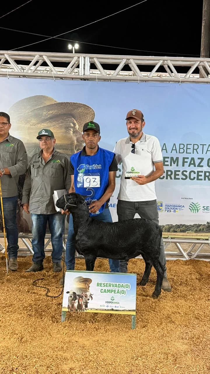 Augusto Cesinha na pista com o troféu, ao lado da ovelha Santa Inês e da placa de reservada campeã